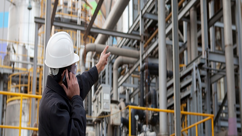 A oil engineer on the phone with a white hat on